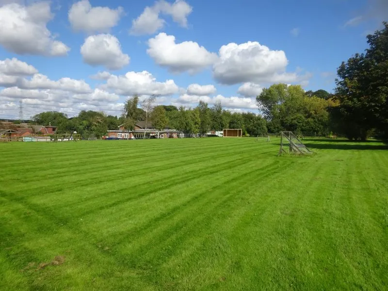 The school playing field with the school and pre-school buildings in the background.